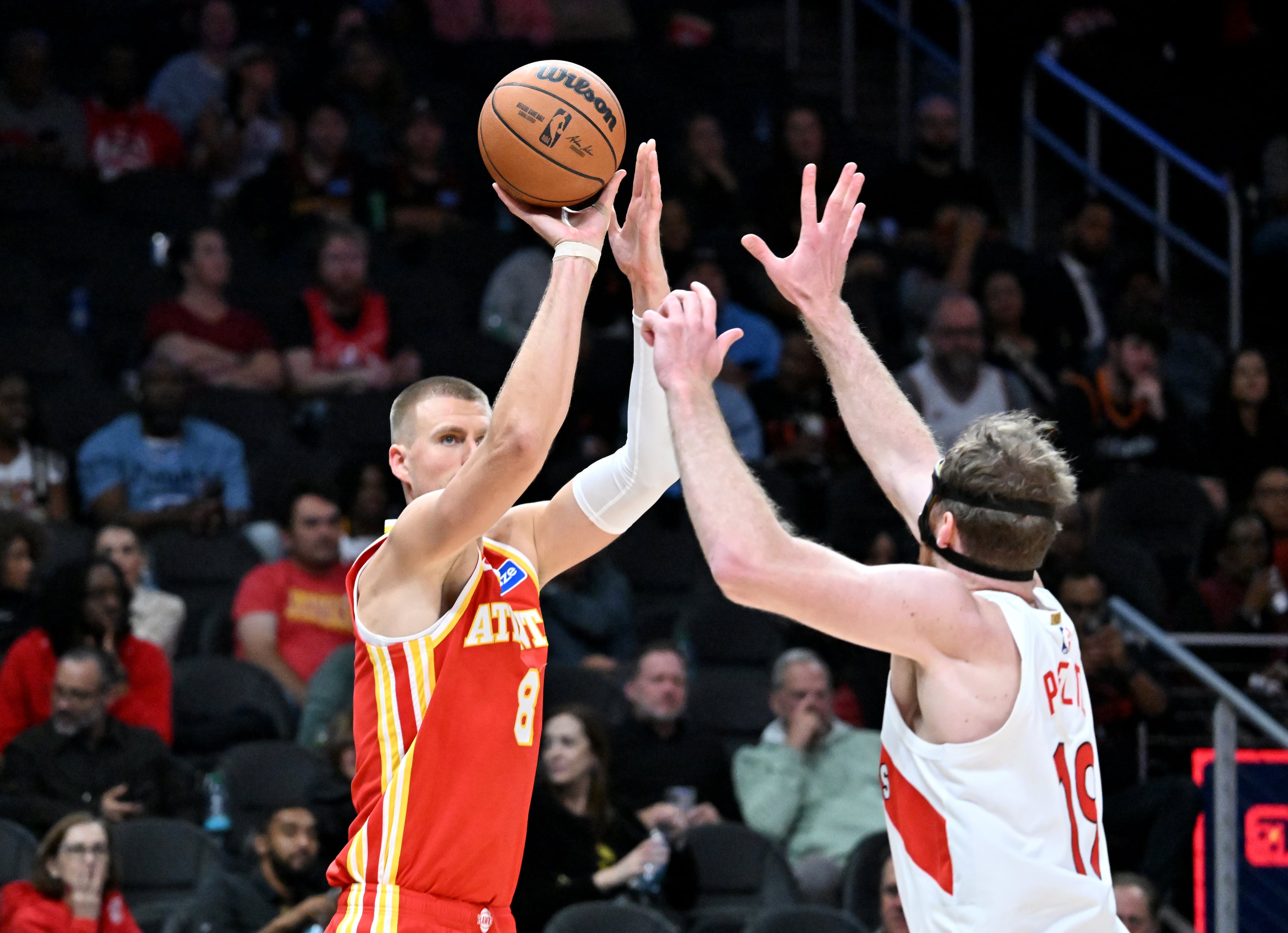 Atlanta Hawks forward/center Kristaps Porziņģis (8) gets off a shot against Toronto Raptors center Jakob Poeltl (19) during the second half in the home opener at State Farm Arena, Thursday, October 22, 2025, in Atlanta. Toronto Raptors won 138-118 over Atlanta Hawks. (Hyosub Shin / AJC)