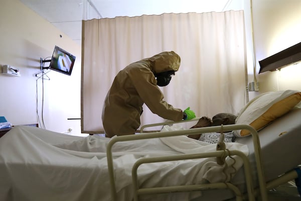 A Georgia Army National Guardsman quietly wipes down a bed railing while trying not to awaken a resident at Legacy Transitional Care and Rehabilitation in Atlanta Sunday, April 19, 2020. Curtis Compton ccompton@ajc.com