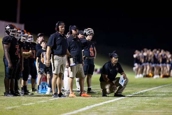 Glascock County head coach Chris Kelley, lower right, watches from the sideline with assistant coaches and players during their game against Warren County at the Glascock County football stadium, Friday, Sept. 19, 2025, in Gibson, Ga. (Jason Getz/AJC)