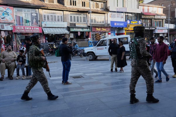 Indian paramilitary soldiers patrol as tourists take pictures at a busy market in Srinagar, Indian controlled Kashmir, Tuesday, April 29, 2025. (AP Photo/Mukhtar Khan)