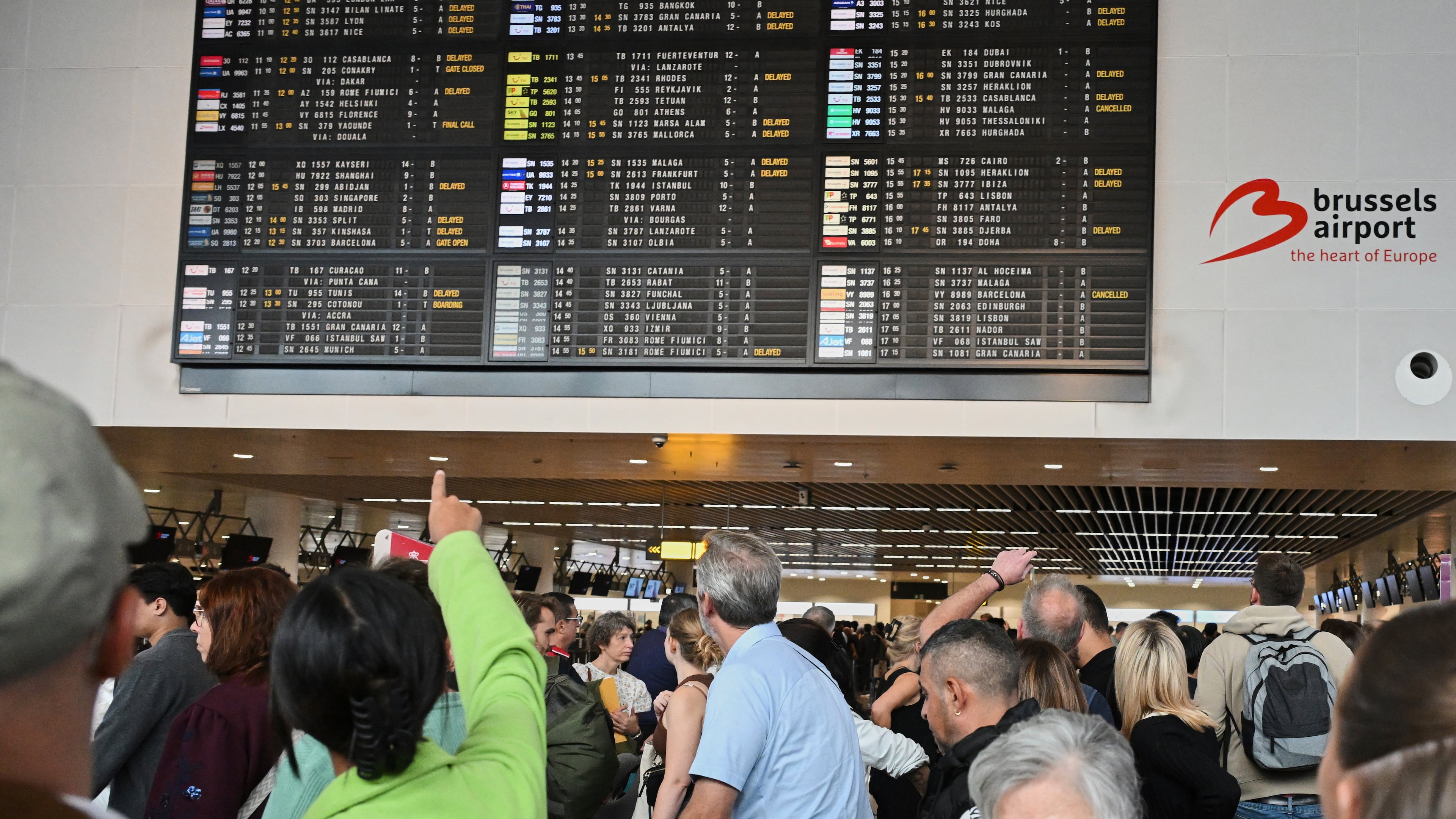 An airport employee points at a departure board after a cyber attack caused delays at Brussels International Airport in Zaventem, Belgium, Saturday, Sept. 20, 2025. (AP Photo/Harry Nakos)