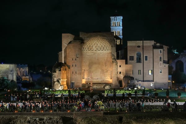 Cardinal Baldassare Reina, Vicar General of Pope Francis for the Diocese of Rome, center holding a cross, leads the procession in front of the Colosseum during the Via Crucis (Latin for 'way of the cross') in Rome, Friday, April 18, 2025. (AP Photo/Andrew Medichini)