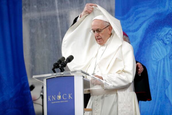 FILE - An aide adjusts Pope Francis' mantle as he delivers his speech at the Knock Shrine, in Knock, Ireland, Aug. 26, 2018. (AP Photo/Gregorio Borgia, File)