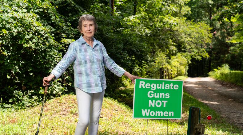Mary Ellen Myers, a member of the Banks County Democratic Committee, poses with a sign she used to display in her yard in Alto. Myers said she found trash, such as drink cans, thrown at the sign, although she's faced little other backlash. “There’s some civility in this county,” said Myers, who has lived in Banks County for more than two decades. (Seeger Gray / AJC)