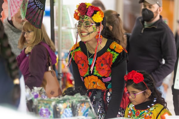 A woman smiles at a vendor at the Atlanta Symphony Orchestra Dia de los Muertos Festival at the Woodruff Arts Center in Atlanta, GA, on Sunday, October 30, 2022.(Photo/ Jenn Finch)