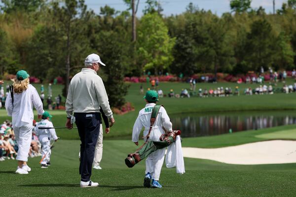 Larry Mize walks with a grandson as he carries his clubs as they walk down the first hole during the Par 3 of the Masters golf tournament at Augusta National Golf Club, Wednesday, April 9, 2025, in Augusta. (Jason Getz/AJC)