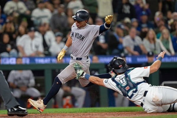 New York Yankees' Oswaldo Cabrera scores a run ahead of a tag by Seattle Mariners catcher Cal Raleigh during the ninth inning of a baseball game, Monday, May 12, 2025, in Seattle. (AP Photo/Stephen Brashear)