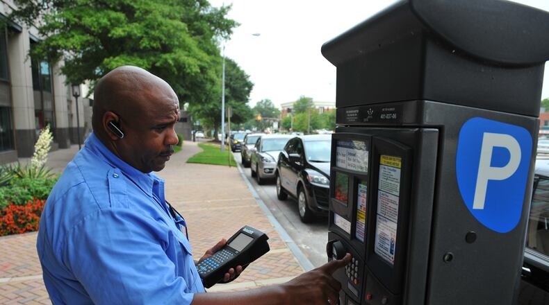 Atlanta: Kevin Brown with ParkAtlanta checks a pay station to determine if any cars are parked in expired spaces Friday August 10, 2012. The pay station communicates with his handheld device, allowing Brown to remotely check for expired spaces.