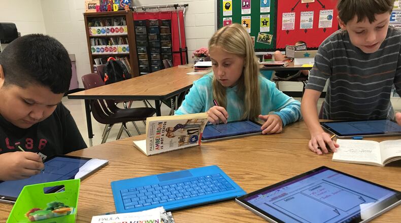 Holly Springs students (left to right) Matthew Rodriguez-Pineda, Klaire Henkle and Maximillian Raiford use technology to illustrate their reading. The Cherokee County school is also a STEM academy.