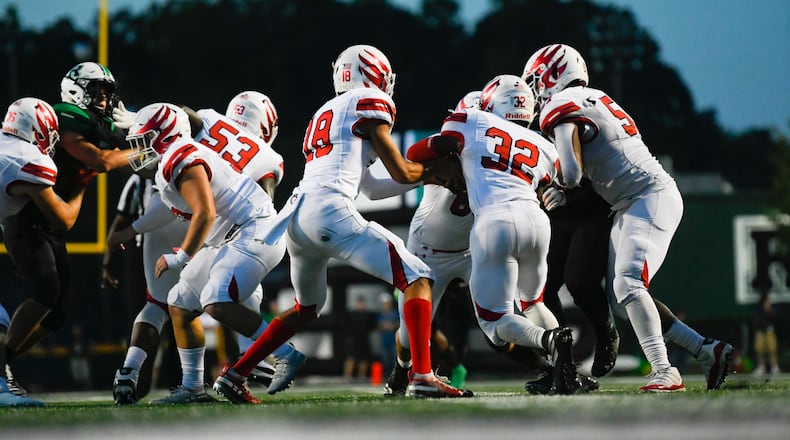 Milton QB Jackson Weaver (18) hands off to RB Ahmad Junearick (32) during the first quarter of a high school football game, Friday, Sept. 20, 2019, in Roswell.