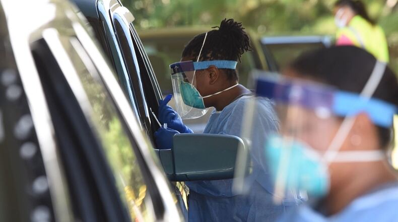 Registered nurses Jesslyn Lewis (center) and Sasha Stewart (Right) conduct COVID-19 tests outside the Glynn County Health Department in Brunswick on July 14, 2020. RYON HORNE / RHORNE@AJC.COM