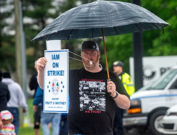 Andy Opgaard, a Pratt & Whitney employee, blows a whistle and holds a sign as he crosses the street to with fellow workers on the picket line at the Silver Lane entrance in East Hartford, Conn., on the first day of their strike, Monday, May 5, 2025. (Aaron Flaum/Hartford Courant via AP)