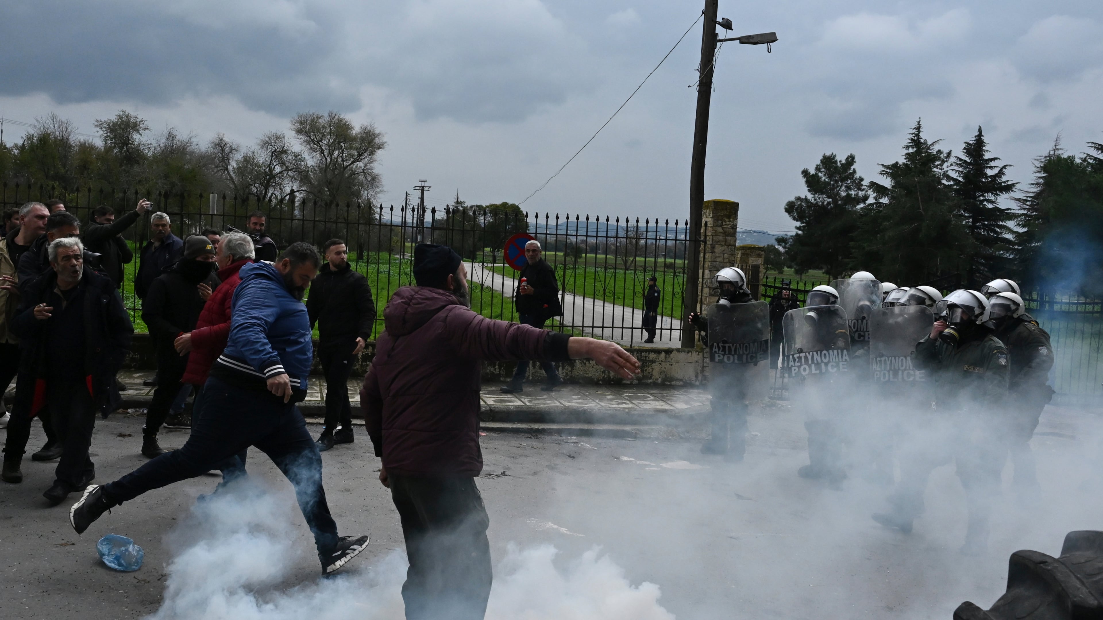 A man kicks a tear gas canister back toward riot police during clashes after farmers tried to block the main access road to Thessaloniki's international airport, northern Greece, on Friday, Dec. 5, 2025, as protests over delays in European Union-backed agricultural subsidy payments escalated. (AP Photo/Giannis Papanikos)
