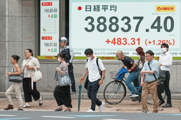 People walk in front of an electronic stock board showing Japan's Nikkei index at a securities firm Tuesday, June 24, 2025, in Tokyo. (AP Photo/Eugene Hoshiko)