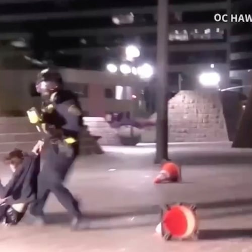 In this image taken from a video provided by OC Hawk, a federal officer drags a demonstrator hit in the face with a projectile fired from close range by an officer during a protest in Santa Ana, Calif., Friday, Jan. 9, 2026. (OC Hawk via AP)