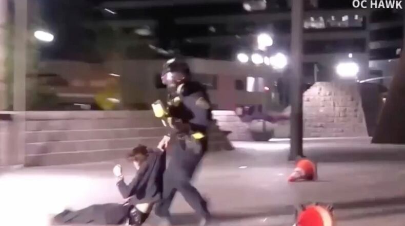 In this image taken from a video provided by OC Hawk, a federal officer drags a demonstrator hit in the face with a projectile fired from close range by an officer during a protest in Santa Ana, Calif., Friday, Jan. 9, 2026. (OC Hawk via AP)