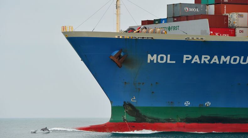Dolphins jump in front of a Paramount cargo ship as the vessel approaches the mouth of the Savannah River in February 2012. Brant Sanderlin bsanderlin@ajc.com
