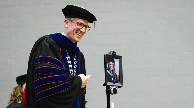 University of West Georgia President Brendan Kelly (left) smiles as he gives a degree virtually to Samantha Conerly, who was unable to attend the ceremony because she is pregnant and on bed rest. The school and Conerly directed a robot with a camera and iPad to talk to Kelly. (Courtesy of University of West Georgia)