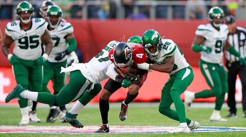 Atlanta Falcons wide receiver Tajae Sharpe (4) is tackled by New York Jets cornerback Brandin Echols (26) and middle linebacker C.J. Mosley (57) during the second half Sunday, Oct. 10, 2021, at the Tottenham Hotspur stadium in London, England. (Ian Walton/AP)