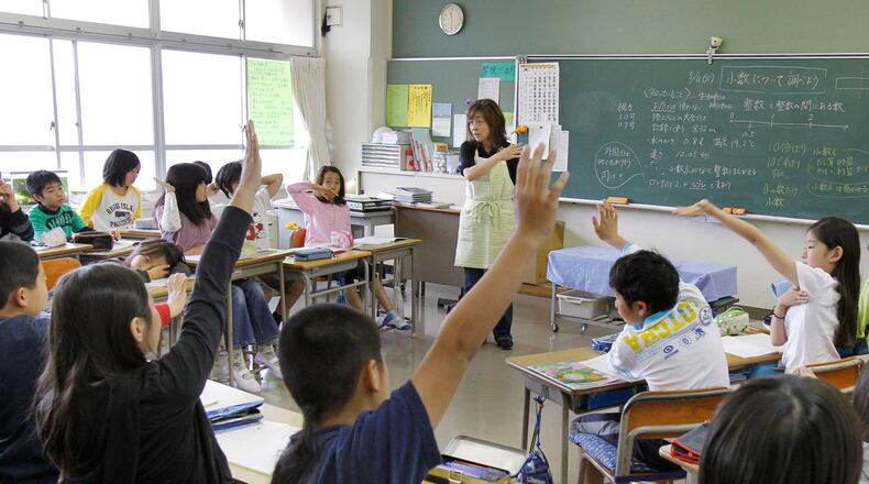 Students at a school in Yokohama, Japan, raise their hands for a math question.