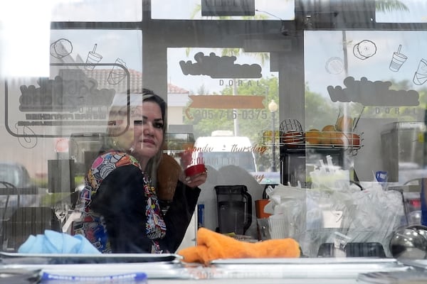 Manager Yrene Bruno is seen through reflective glass as she sits inside a franchise of "Sabor Venezolano," one of 18 businesses owned by Wilmer Escaray which employ scores of Venezuelan immigrants with Temporary Protected Status (TPS) who are now potentially exposed to deportation, in Doral, Fla., Tuesday, May 20, 2025. (AP Photo/Rebecca Blackwell) (AP Photo/Rebecca Blackwell)
