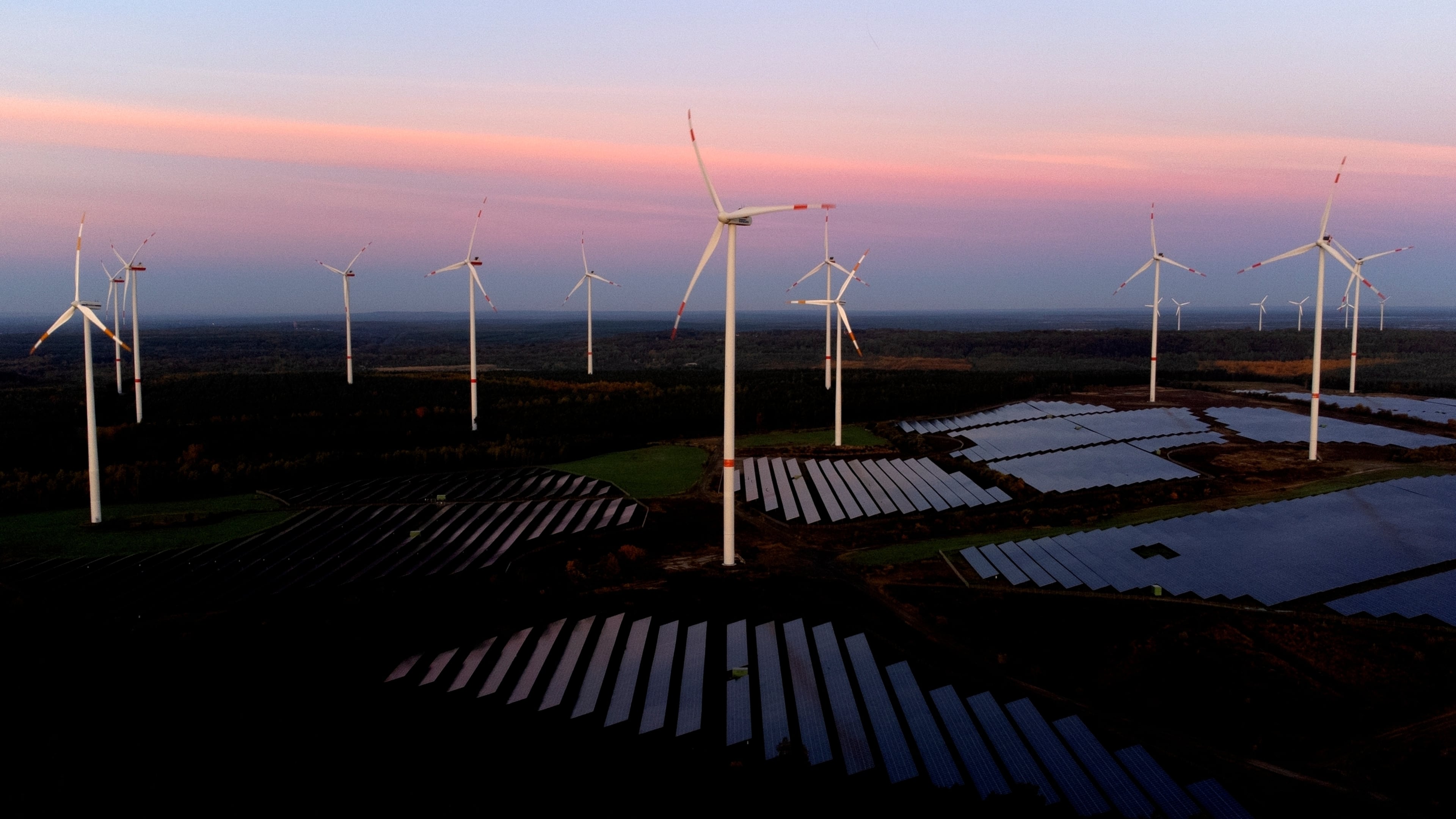 FILE - Wind turbines operate as the sun rises at the Klettwitz Nord solar energy park near Klettwitz, Germany, Oct. 16, 2024. (AP Photo/Matthias Schrader, File)