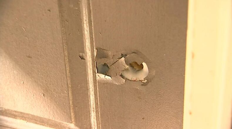 A bullet hole left in a neighbor’s door after a gun fired while the owner was cleaning it. (Credit: Channel 2 Action News)