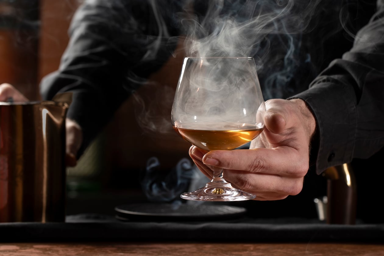 Mixologist Brendan Seery lights cinnamon and clove powder to make the smoke in the aptly named Kemuri cocktail at Himitsu. (Courtesy of Lara Kastne)