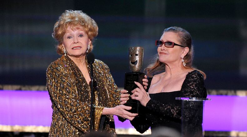 FILE- In this Jan. 25, 2015, file photo, Carrie Fisher, right, presents her mother Debbie Reynolds with the Screen Actors Guild life achievement award at the 21st annual Screen Actors Guild Awards at the Shrine Auditorium in Los Angeles. "La La Land" star Ryan Gosling thanked Reynolds at the Palm Springs Film Festival on Monday, Jan. 2, 2017, for serving as an inspiration to the cast and crew of the film. (Photo by Vince Bucci/Invision/AP, File)