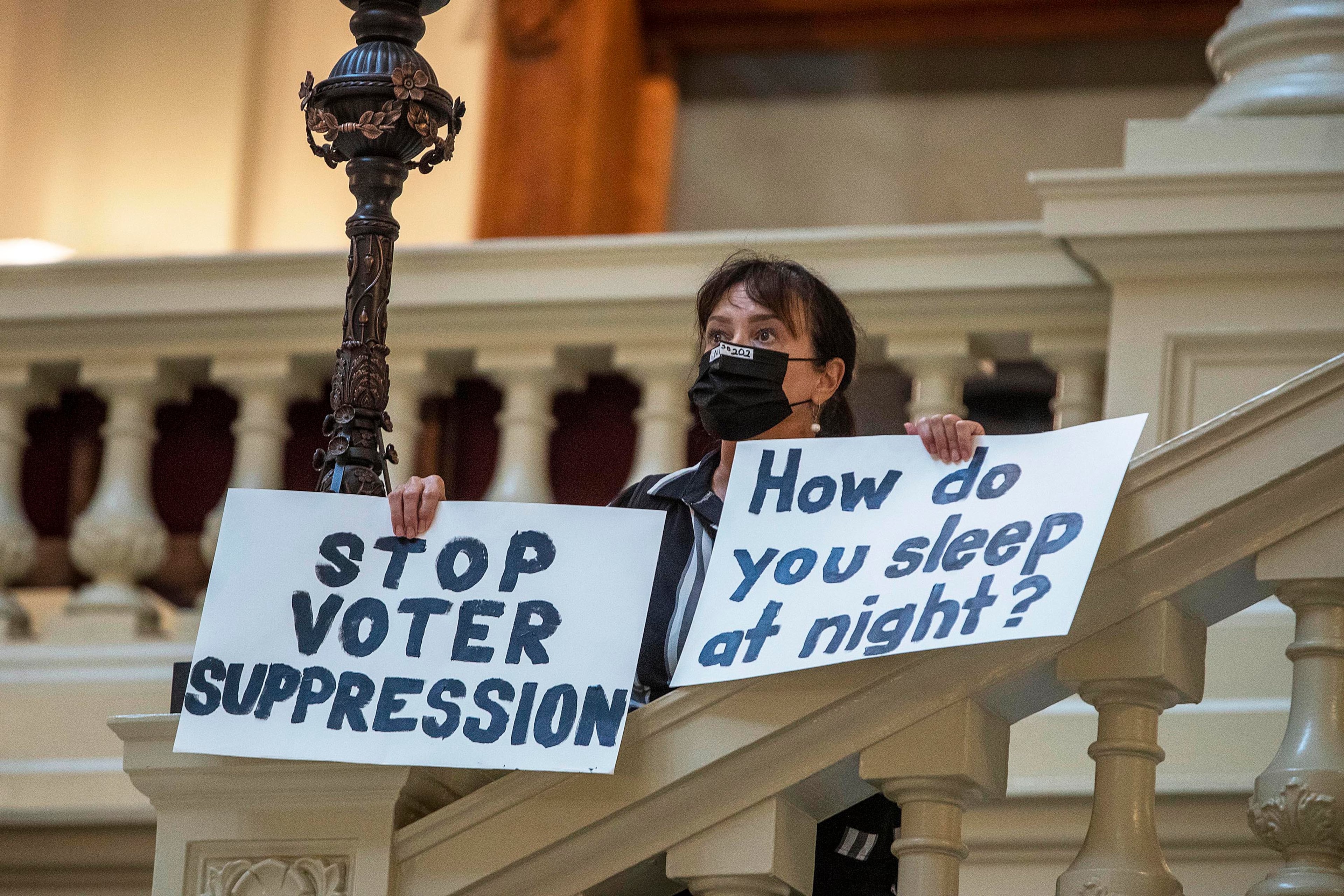 Ann White of Roswell holds protest signs on the North Wing stairs of the Georgia State Capitol building in Atlanta, Thursday, March 25, 2021. (Alyssa Pointer/AJC)
