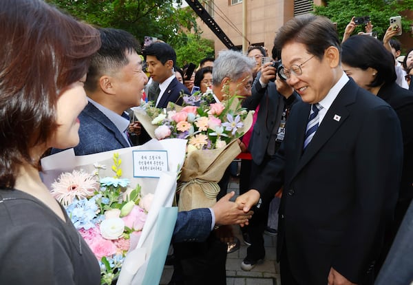 South Korea's newly elected President Lee Jae-myung, right, greets his neighbors and supporters in front of his house in Incheon, South Korea, Wednesday, June 4, 2025. (Han Sang-kyun/Yonhap via AP)
