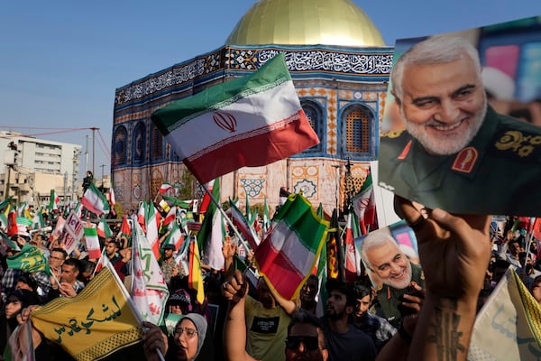 Demonstrators wave Iranian flags and hold posters of the late Iranian Revolutionary Guard Gen. Qassem Soleimani, who was killed in a U.S. strike in Iraq in 2020, in front of a model of Jerusalem's Dome of the Rock mosque during a rally marking the Muslim Shiite holiday of Eid al-Ghadir, which commemorates the Prophet Muhammad naming his successor, Ali, who is revered as the first Shiite imam, in Tehran, Iran, Saturday, June 14, 2025. (AP Photo/Vahid Salemi)