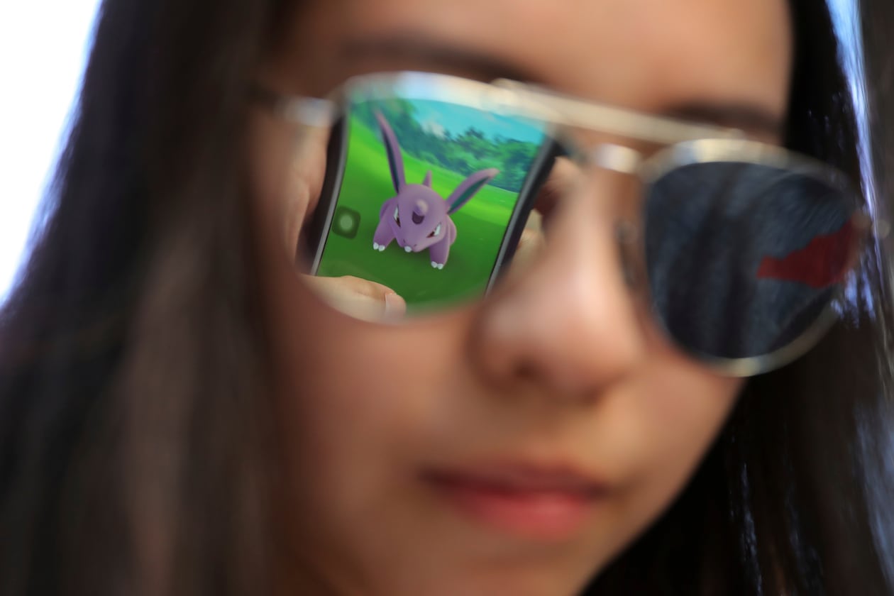 FILE - A mobile screen is reflected on a fan's sunglasses as she plays "Pokemon Go" in Hong Kong, on July 25, 2016. (AP Photo/Kin Cheung, File)