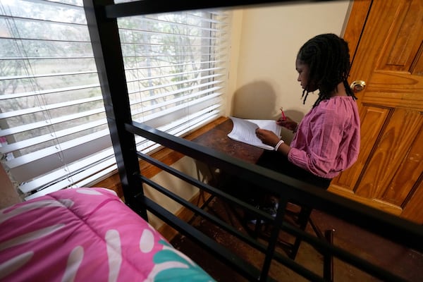 Hailey Robinson, 8, works on homework after school in a room she shares with her mother and brother at Mission of Yahweh women's shelter on Tuesday, April 1, 2025, in Houston. (AP Photo/Ashley Landis)