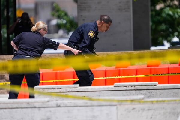 Law enforcement officers investigate the scene where a Harris County deputy and a suspect were shot outside The Family Law Center in Houston, Monday, April 21, 2025. (Brett Coomer/Houston Chronicle via AP)