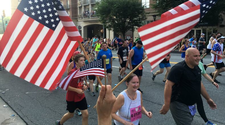 July 4, 2016 Atlanta: A fan waves flags and cheers runners on Cardiac Hill during the AJC Peachtree Road Race on Monday morning July 4, 2016. Ben Gray / bgray@ajc.com