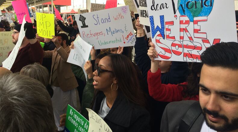 Protesters carry signs Sunday at Atlanta Hartsfield-Jackson International Airport. They are protesting new limits on refugees and immigration imposed by President Donald Trump.