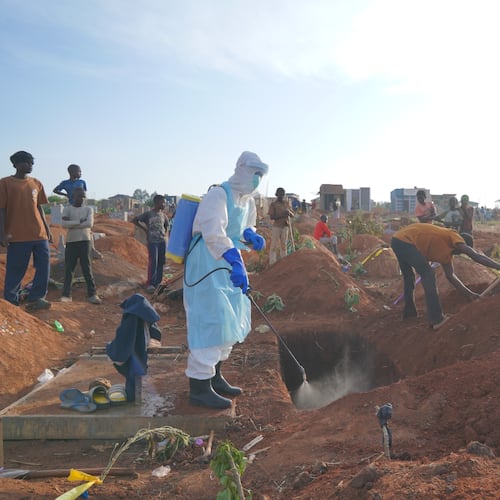 A health worker sprays disinfectant in a freshly dug grave for the body of Jacques Lobo Dhena, who died of Ebola, in Bunia, Ituri province, eastern Congo, Wednesday, Aug. 12, 2026. (AP Photo/Dieudonne Dirole)