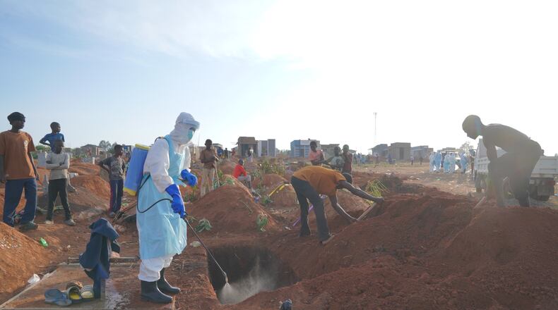 A health worker sprays disinfectant in a freshly dug grave for the body of Jacques Lobo Dhena, who died of Ebola, in Bunia, Ituri province, eastern Congo, Wednesday, Aug. 12, 2026. (AP Photo/Dieudonne Dirole)