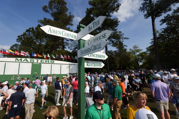 Patrons at Augusta National walk around a sign posting directions to famous areas of interest.