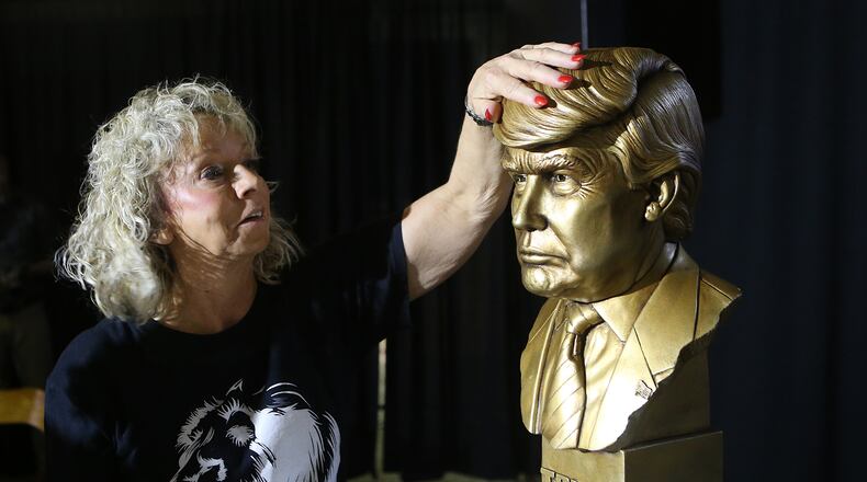 Debbie Dooley, a tea party activist, rubs the brass head of a Donald Trump statue for luck on the stage at the Corey Center during a Trump watch party on Tuesday. Curtis Compton, ccompton@ajc.com
