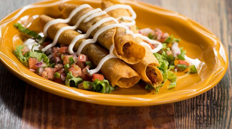 Chicken Flautas with shredded chicken, cotija cheese, onion and poblano in a corn tortilla, topped with lettuce, pico and cilantro with sour cream and queso. Photo credit- Mia Yakel.