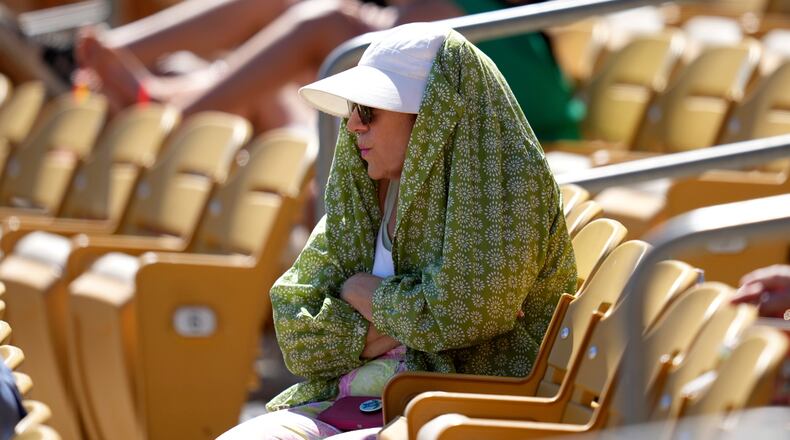 FILE - A baseball fan tries to shield from the sun during the fourth inning of a spring training baseball game between the Chicago White Sox and the Athletics, March 17, 2026, in Phoenix. (AP Photo/Ross D. Franklin, File)