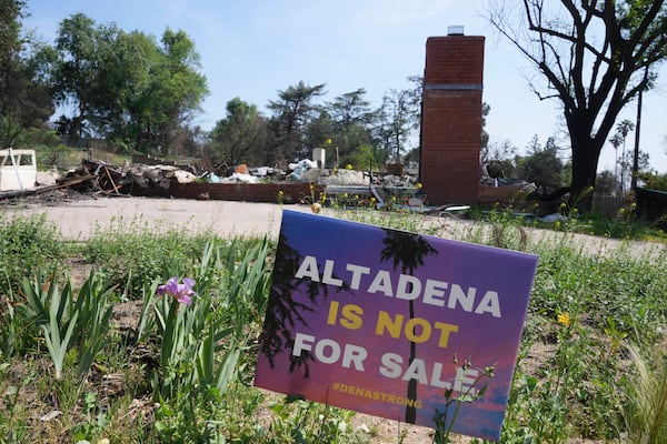 A sign reads "Altadena is not for sale" in front of a fire-damaged property in Altadena, Calif., Tuesday, April 22, 2025. (AP Photo/Damian Dovarganes)