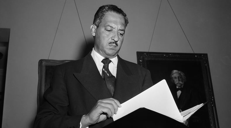 Waist-up view of Thurgood Marshall holding book. Photo circa 1955.