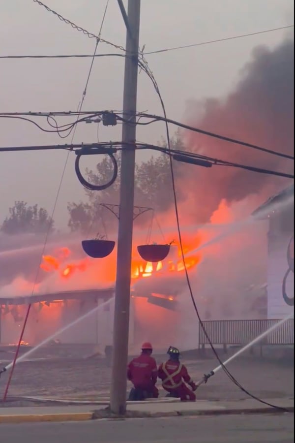 In this photo provided by Evan Bell firefighters combat the wildfires as they consumed Robertson Trading, a general store, in La Ronge, Saskatchewan on June 3, 2025. (Evan Bell via AP)