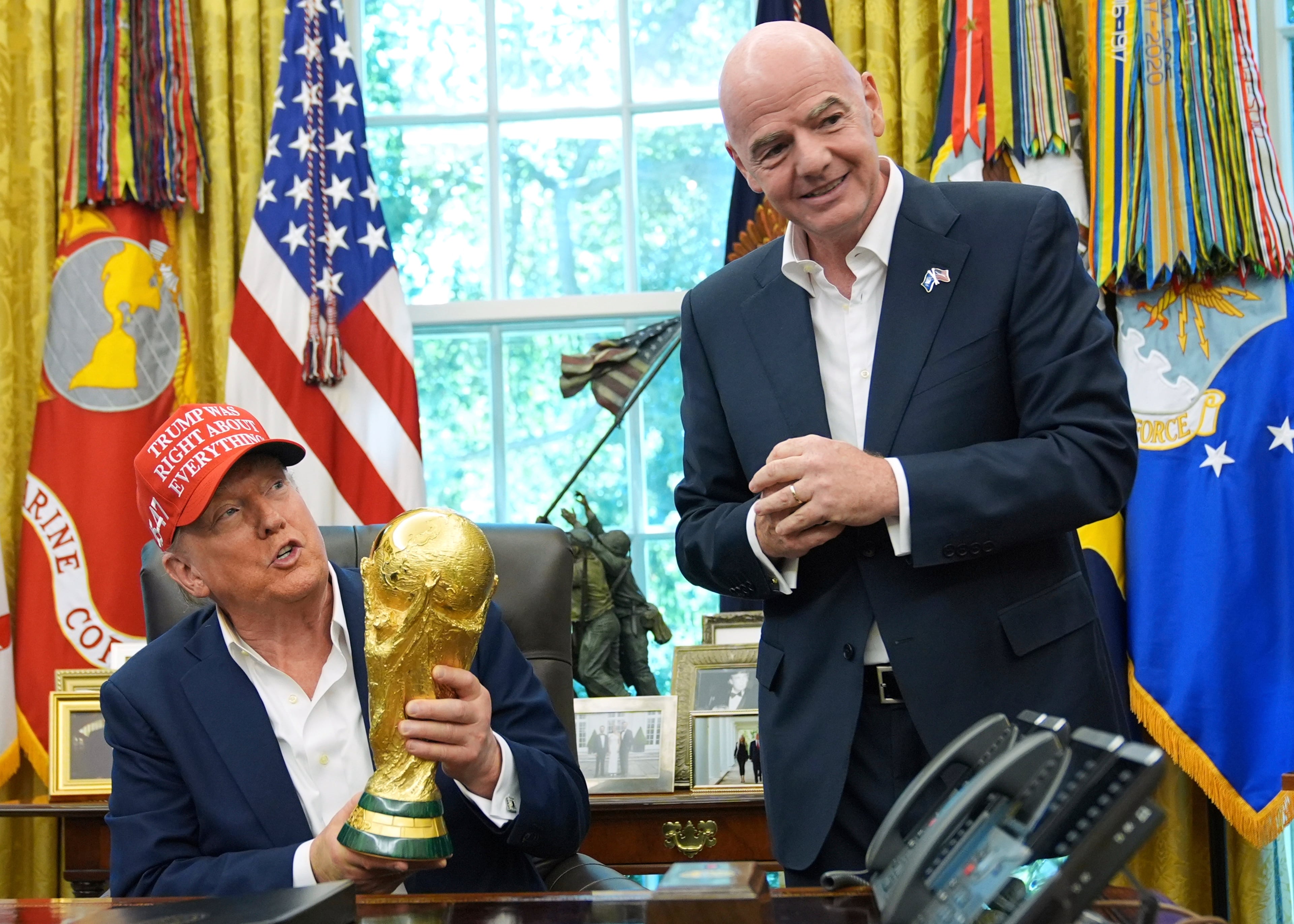 FILE - President Donald Trump holds the FIFA World Cup Winners Trophy as FIFA President Gianni Infantino looks on during an announcement in the Oval Office of the White House, Aug. 22, 2025, in Washington. (Jacquelyn Martin/AP)