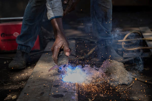 Mahamudu Bitego, a welder, whose business is powered in part by solar energy, works in Goma, Congo, May 23, 2025. (AP Photo/Moses Sawasawa)