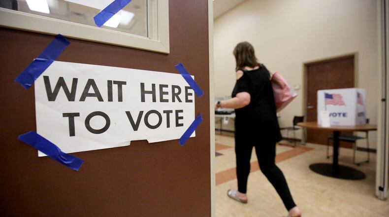 “Wait here to vote,” is shown as a voter walks toward voting booths. Fulton County is planning to open more early voting locations for a September special election. (JASON GETZ/SPECIAL TO THE AJC) AJC FILE PHOTO