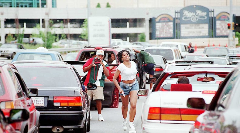 A woman runs back to her car after posing quickly for another Freaknik participant near Phipps Plaza and Lenox Mall. After the malls closed, traffic came to a standstill on Peachtree and Lenox roads during the 1995 gathering.
